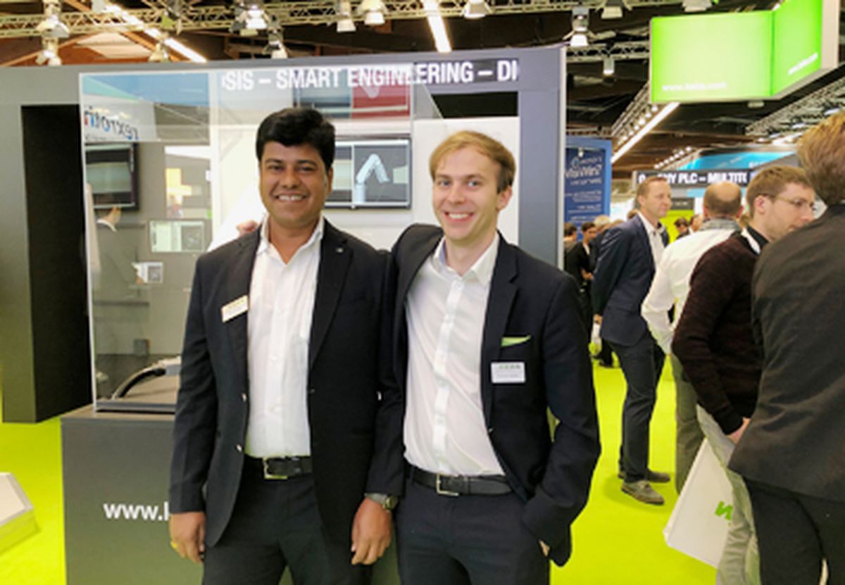 Two people standing together at a trade fair booth, representing automation and engineering solutions in a networking and exchange setting.