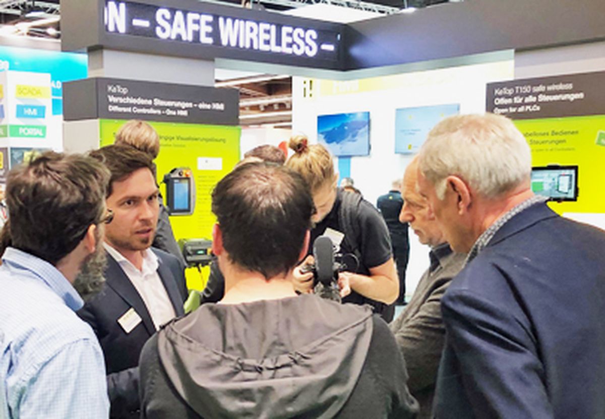 Several people discussing solutions for secure wireless communication in industrial automation at a trade fair booth.