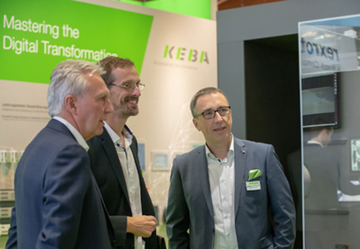 Several people engaged in a professional discussion at a trade fair booth about digital transformation and industrial automation topics.