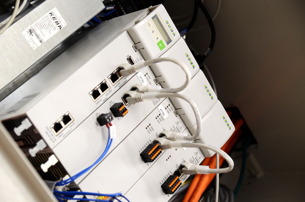 Primo piano di diversi moduli di controllo KEBA con cavi di rete e interfacce collegati all’interno di un quadro di controllo. L’immagine illustra la tecnologia di controllo potente e connessa per sistemi di automazione industriale.