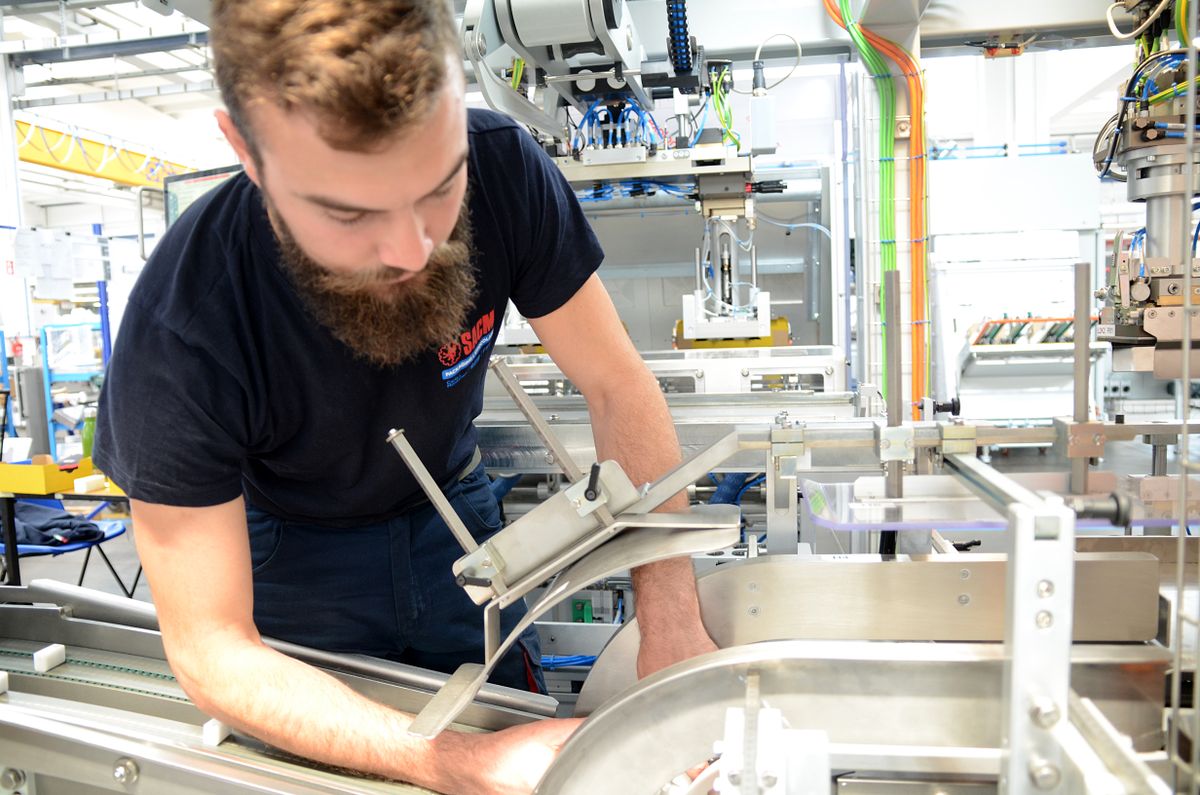 Tecnico che regola un impianto di produzione automatizzato con componenti meccanici, sensori e cablaggi visibili. L’immagine rappresenta la collaborazione tra SACMI e KEBA per l’integrazione di soluzioni di automazione intelligenti.