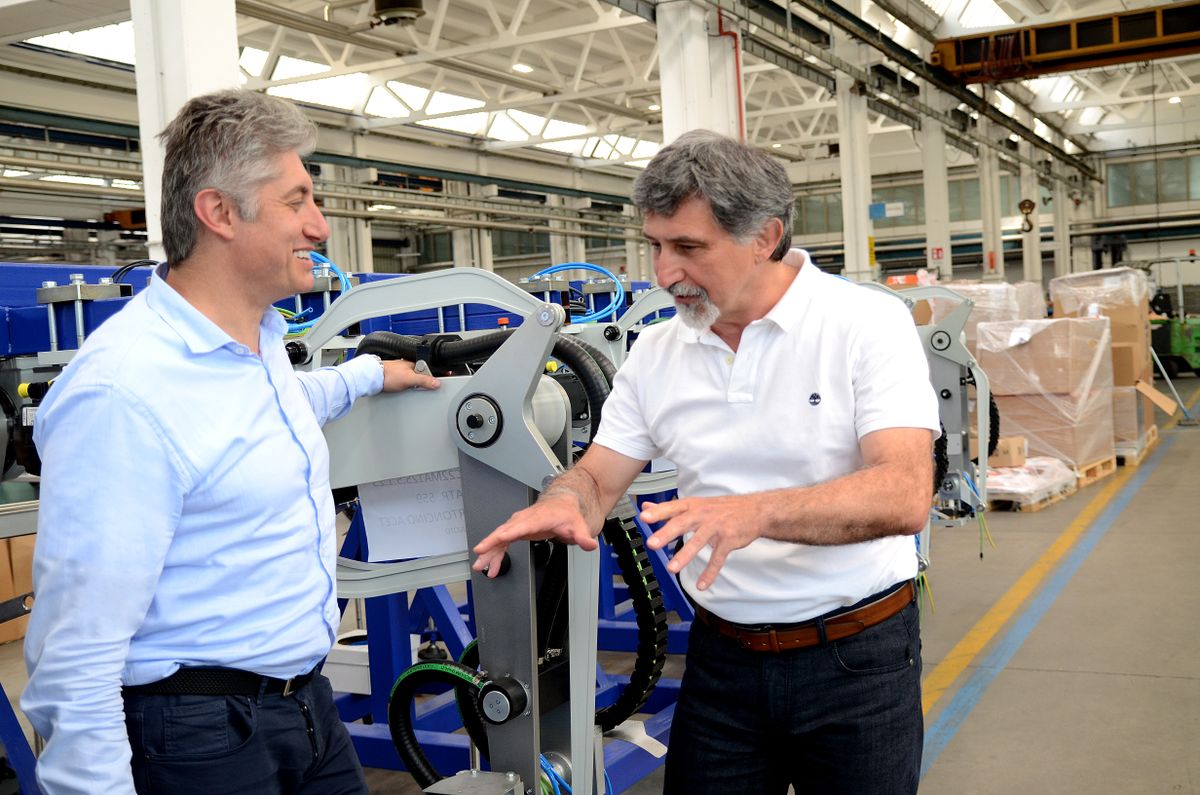 Due professionisti discutono in uno stabilimento di produzione accanto a una macchina automatizzata. L’immagine rappresenta la partnership, la competenza tecnica e la collaborazione tra SACMI e KEBA nell’automazione industriale.