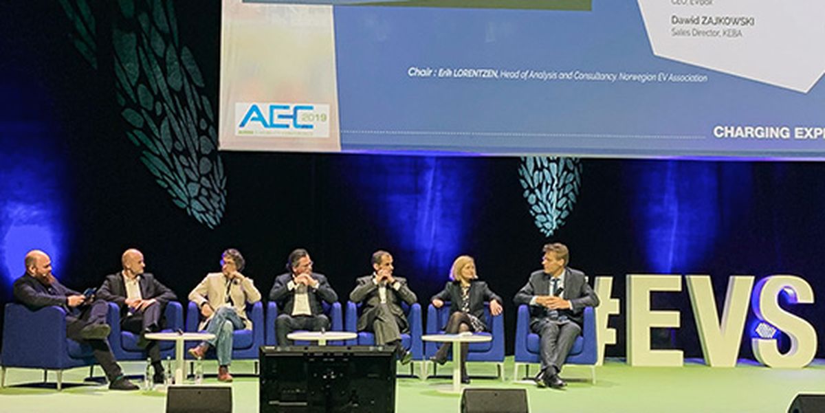 Table ronde lors d'une conférence sur la mobilité électrique avec sept expert·e·s sur scène devant les lettres EVS – discussion sur l'infrastructure de recharge et les enjeux futurs de la mobilité électrique.