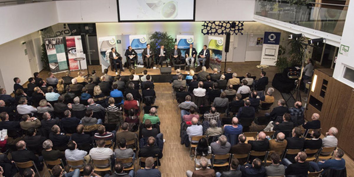 Eine Podiumsdiskussion vor großem Publikum in einem Konferenzsaal mit mehreren Referenten auf der Bühne. Die Veranstaltung behandelt Themen rund um Technologie oder Innovation.