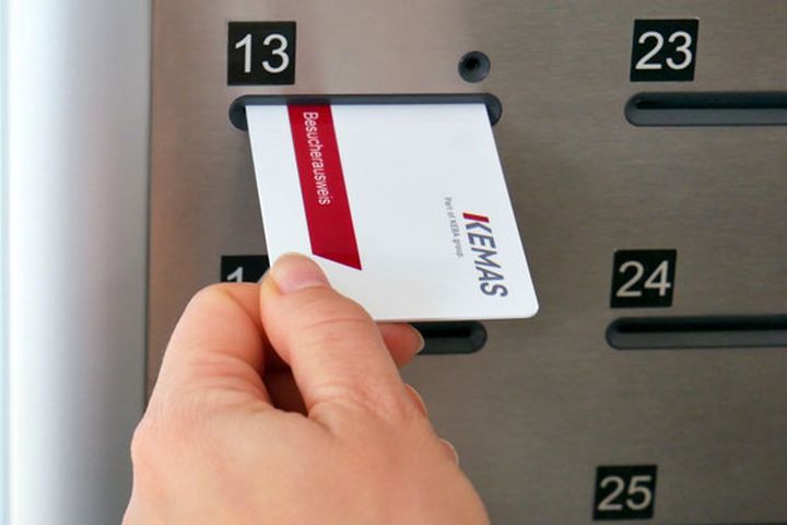 A hand inserts a KEMAS visitor card into a key compartment labeled 13.