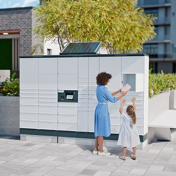 A woman with a child is picking up a parcel at a loxmate parcel station.