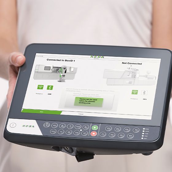 Dispositivo portatile di controllo KEBA con touchscreen e visualizzazione dello stato, connesso in modalità wireless a una macchina.