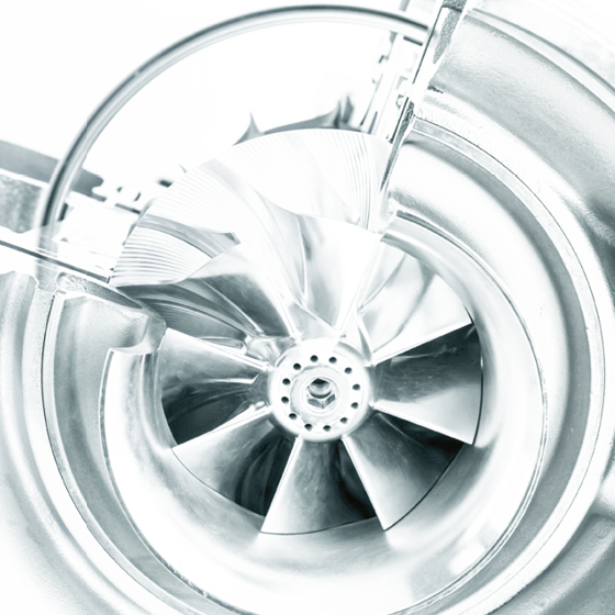 Close-up of a metallic turbine or fan wheel with precisely machined blades. The image represents high-performance mechanics, energy efficiency, and technical precision in industrial manufacturing.