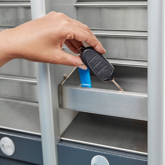 A hand is placing a key into a KEMAS key handover terminal.