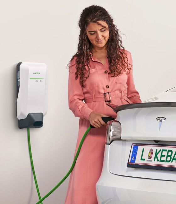Woman charging her electric company car at home with a white KEBA KeContact P40 Company Car Wallbox, enabling easy reimbursement of charging costs by her employer.