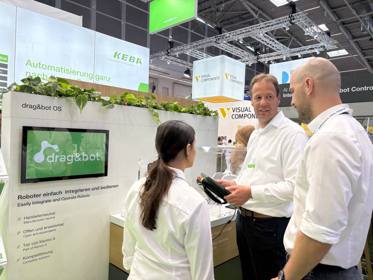 Drei Personen stehen am KEBA-Messestand vor dem drag&bot-Display und diskutieren eine Roboterlösung.