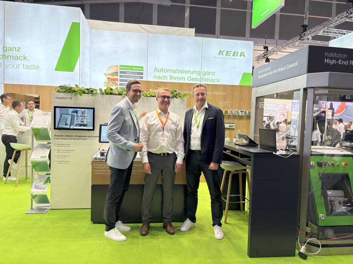 Drei Männer posieren lächelnd vor dem KEBA-Messestand mit dem Slogan „Automatisierung ganz nach Ihrem Geschmack“ und einer Präsentation der Kemro X Plattform.