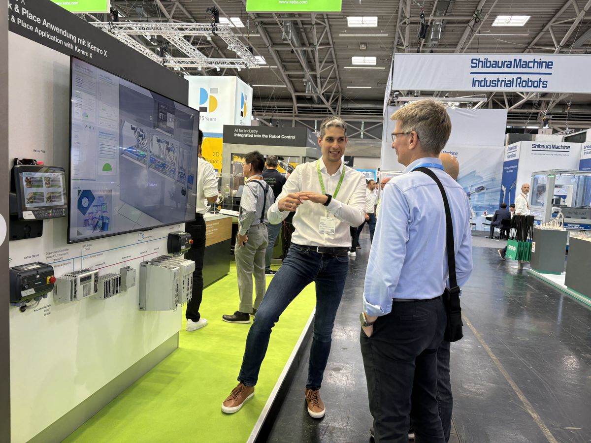 Ein Mann demonstriert auf einer Messe industrielles Automatisierungsequipment von KEBA einem Besucher vor einem Bildschirm.