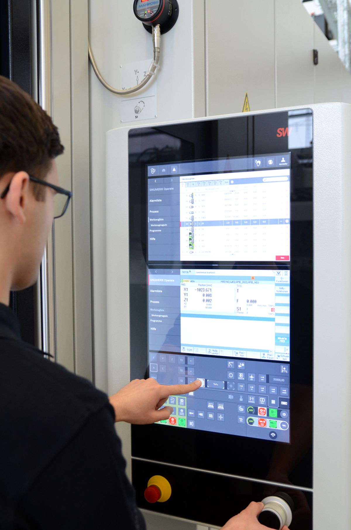 Operator working on an industrial machine control with a large touchscreen displaying and adjusting process parameters and control commands – example of modern HMI technology.