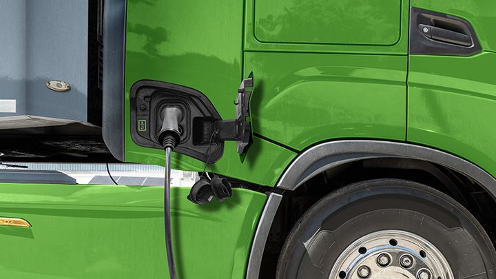 Close-up of a charging cable connected to a green electric truck.