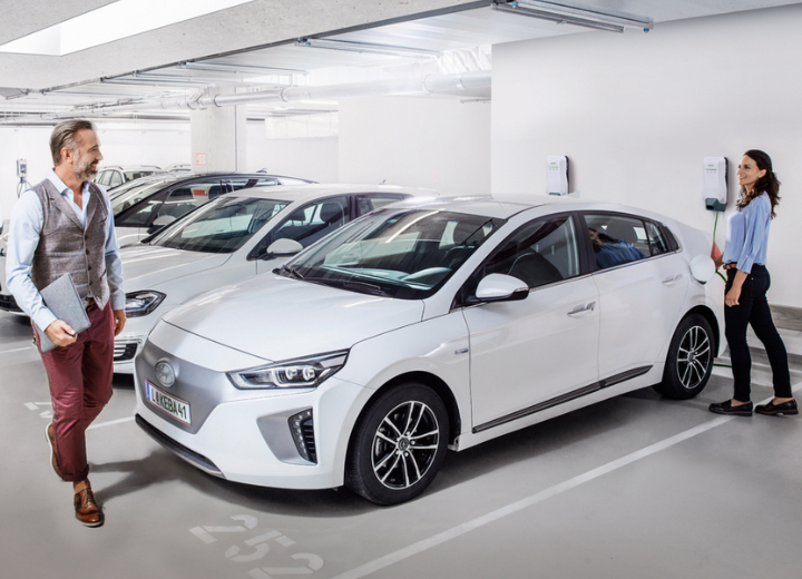 Ein Handwerker mit Schutzhelm installiert eine KEBA-Wallbox an einer Wand. Er arbeitet konzentriert mit Werkzeugen.