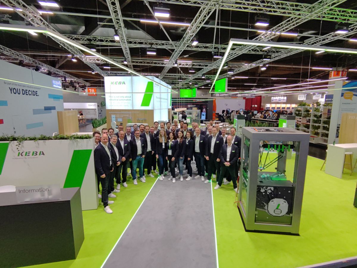 Large group of staff standing together at a trade fair booth, presenting industrial automation solutions during an exhibition