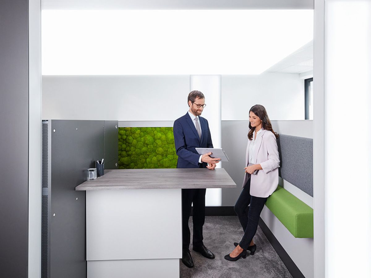 Ein Bankberater zeigt einer Kundin in einer modernen Filiale ein Dokument auf einem Tablet.