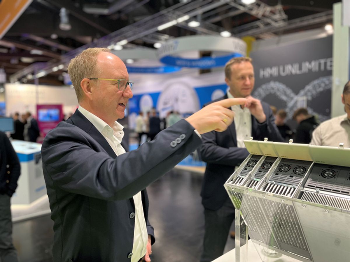 Several people examining and discussing an opened automation device during a technical product demonstration at a trade fair.