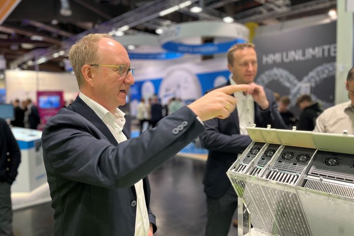 Several people examining and discussing an opened automation device during a technical product demonstration at a trade fair.