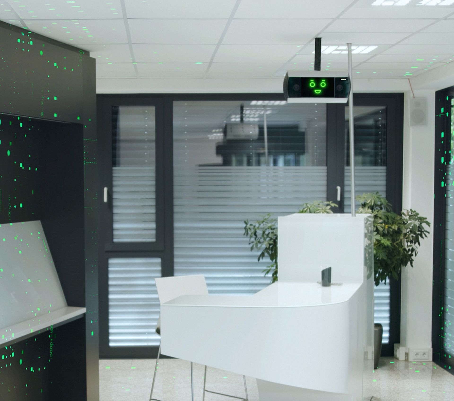 A modern reception area with a white desk and a ceiling-mounted digital sensor displaying a friendly smiley face. Windows with blinds and green plants are visible in the background.