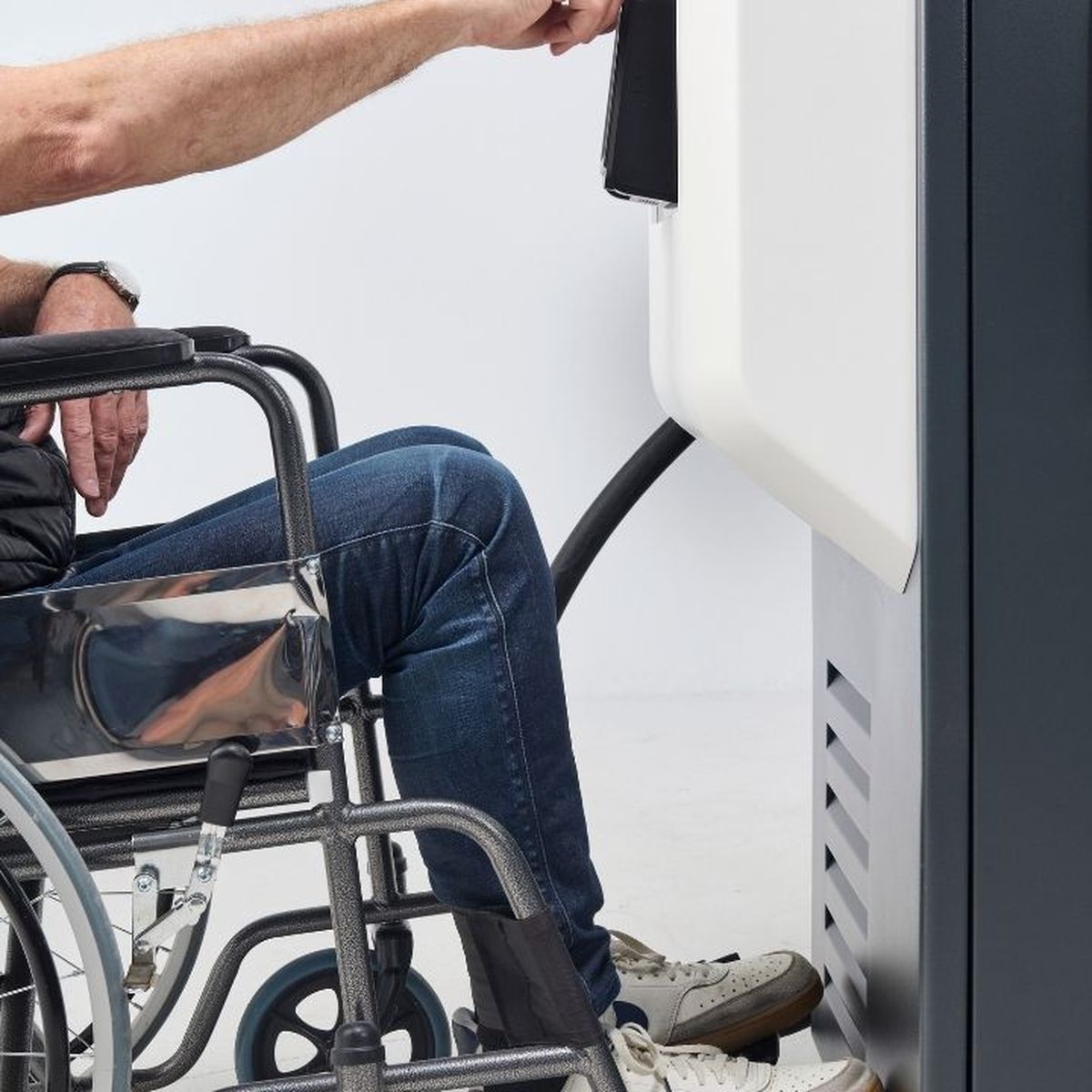 Eine Person im Rollstuhl bedient die KeContact DCA20. Die Aufnahme zeigt die barrierefreie Erreichbarkeit der Bedienelemente aus sitzender Position.
