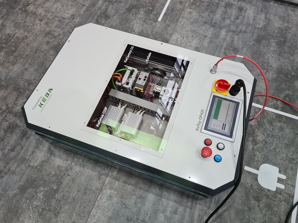 Portable KEBA testing and demonstration unit with a transparent window showing integrated drive and control components. A control panel with touchscreen, emergency stop button and operator controls is mounted on the right. The device represents a compact test solution for drive technology and control systems.