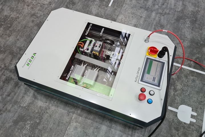 Portable KEBA testing and demonstration unit with a transparent window showing integrated drive and control components. A control panel with touchscreen, emergency stop button and operator controls is mounted on the right. The device represents a compact test solution for drive technology and control systems.