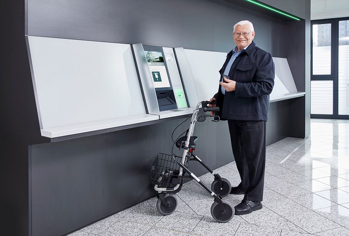 Älterer Herr mit Rollator bedient einen KEBA Cash Recycler