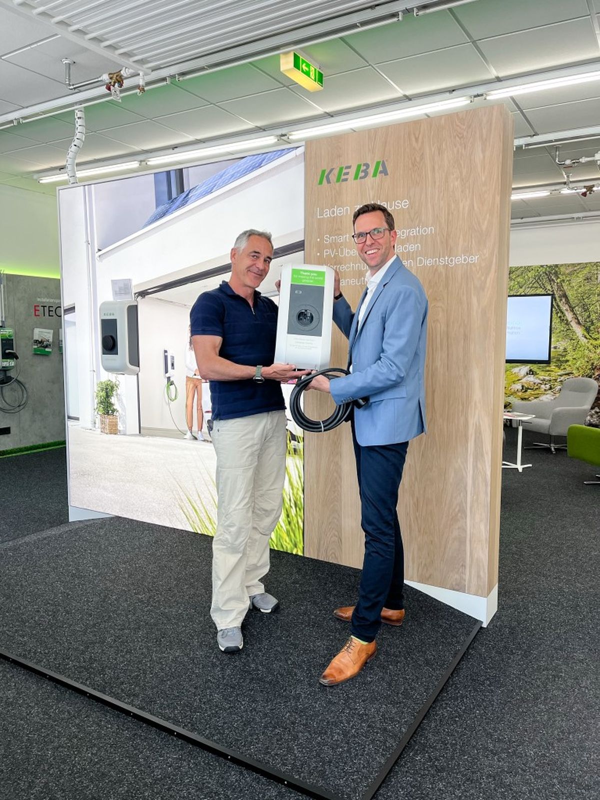 Übergabe der KEBA Wallbox an Christian Clerici auf einem Messestand.