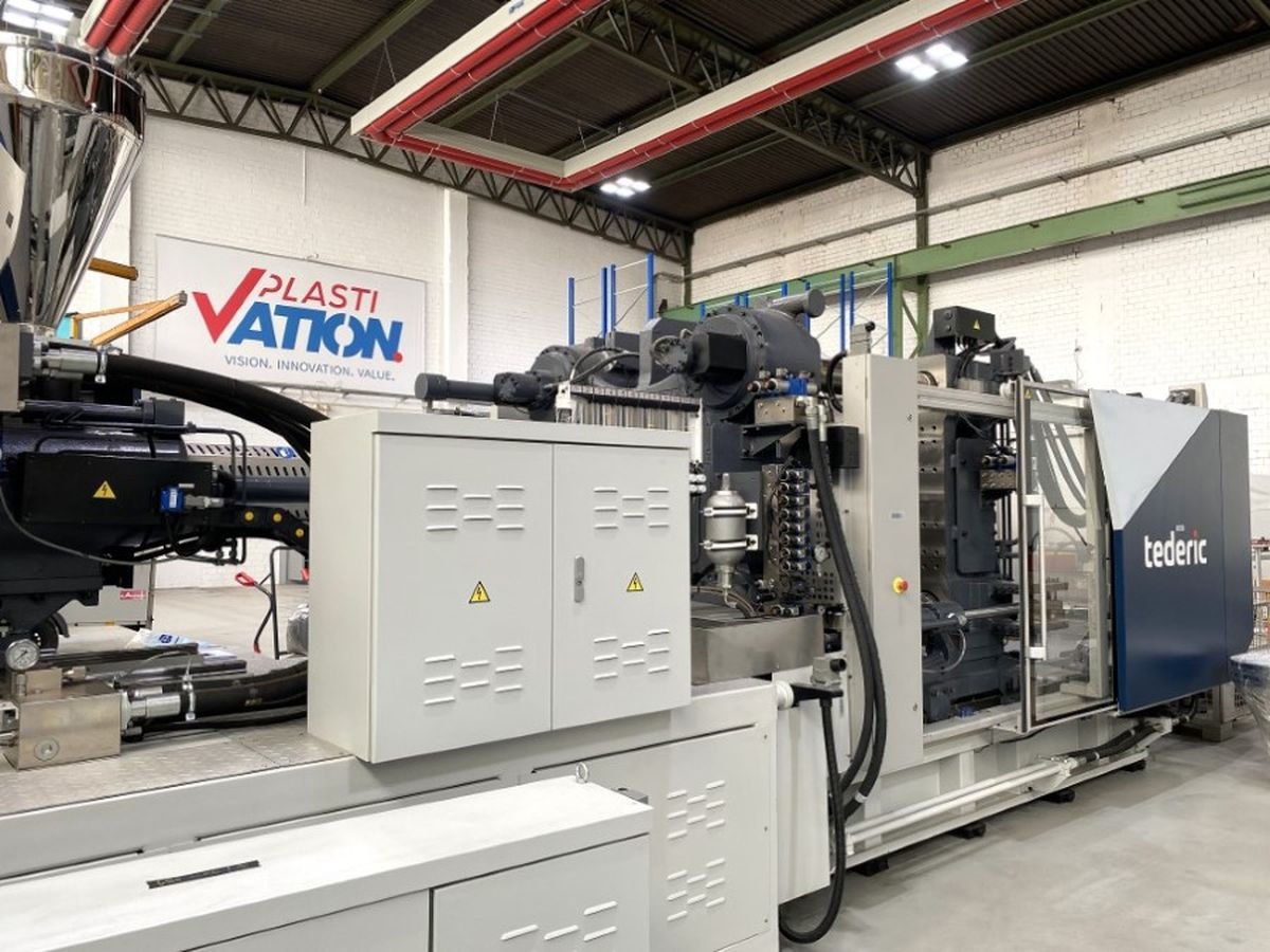 Side view of a Tederic injection molding machine in a clean, well-lit industrial space. The PlastiVation logo is visible on the back wall, emphasizing the professional and organized setting.
