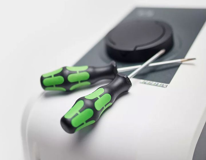 Zwei grüne Schraubendreher liegen auf einer KEBA-Ladestation für Service- und Supportleistungen.