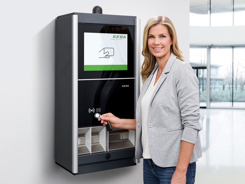 A woman in a gray blazer operates a KEBA handover terminal.