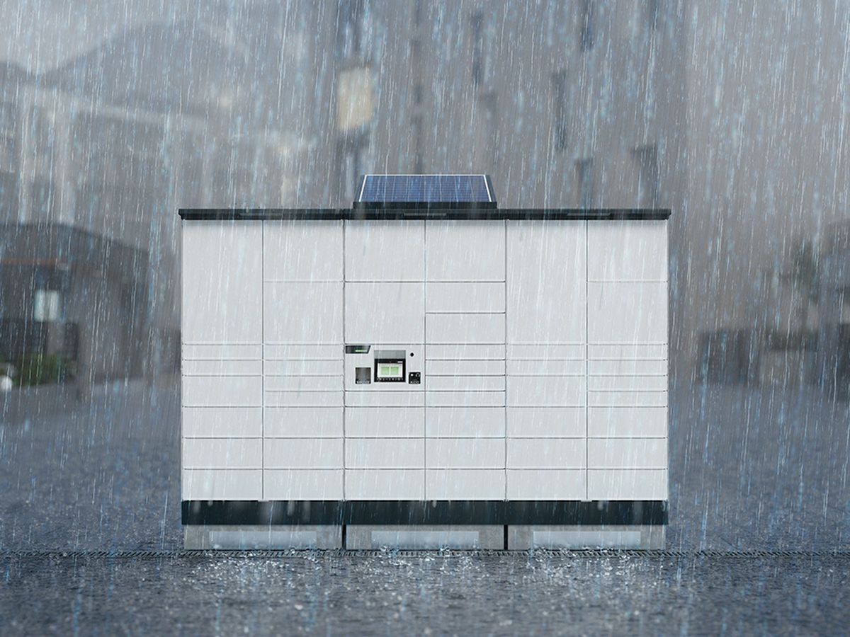 White parcel locker set in a rainy urban environment with blurred background buildings.
