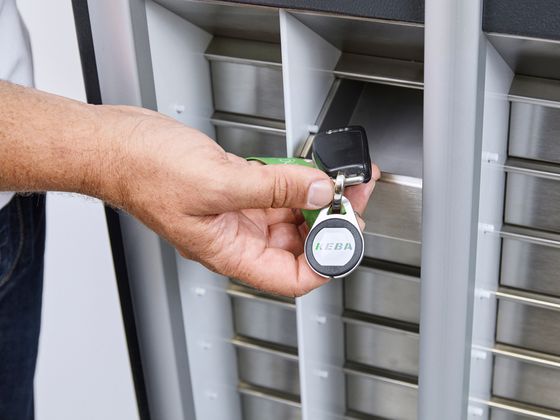 Person holding a digital key up to a vehicle pool management system.
