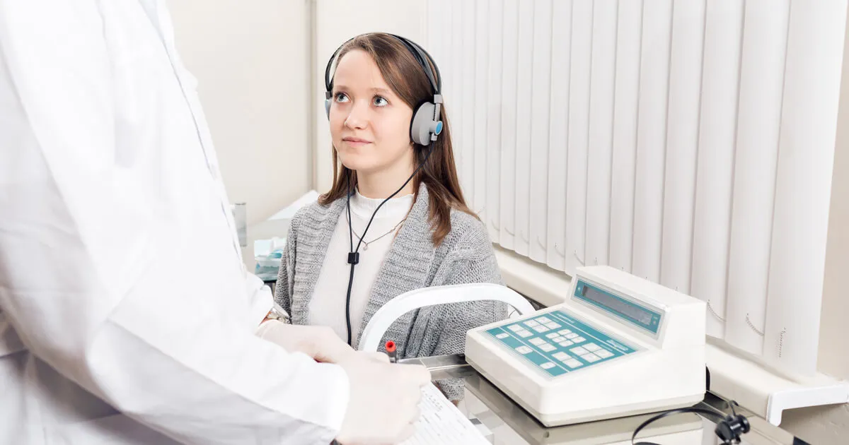A patient listens for the softest sounds they can hear during a hearing test.