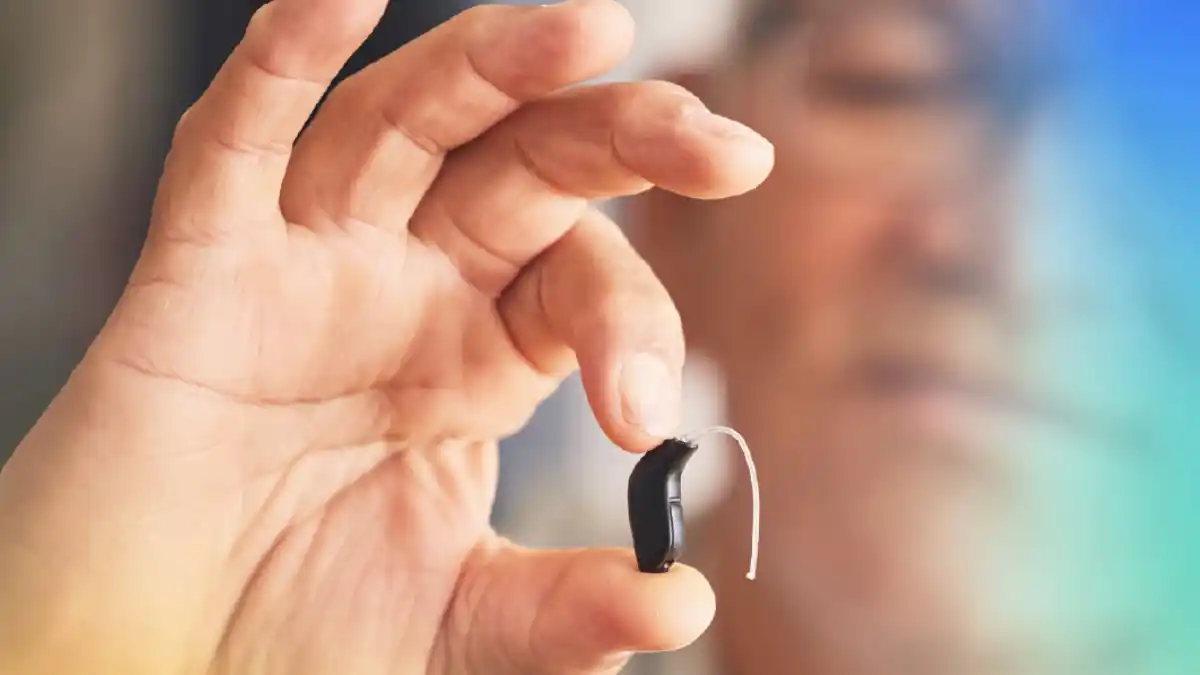 Tiny black hearing aid held in someone's hands