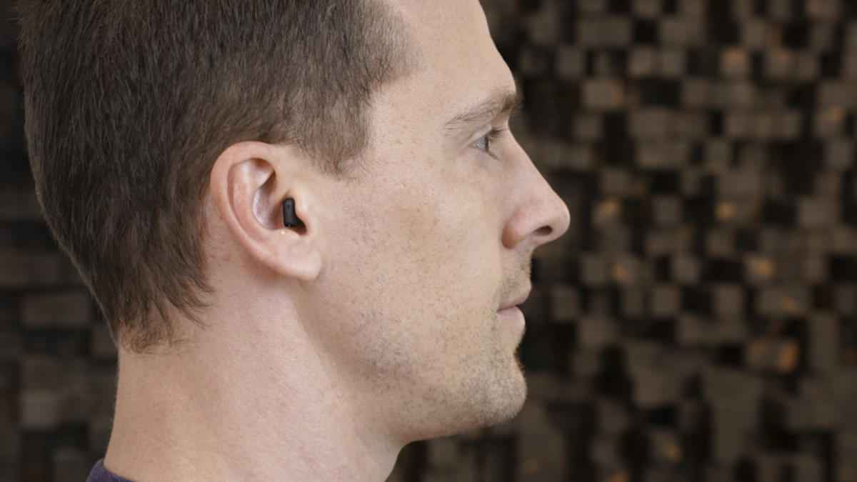 The tiny black Signia IX can be seen at the opening of the author's ear canal only.