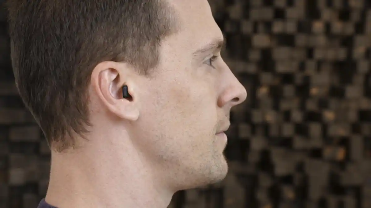 The tiny black Signia IX can be seen at the opening of the author's ear canal only.