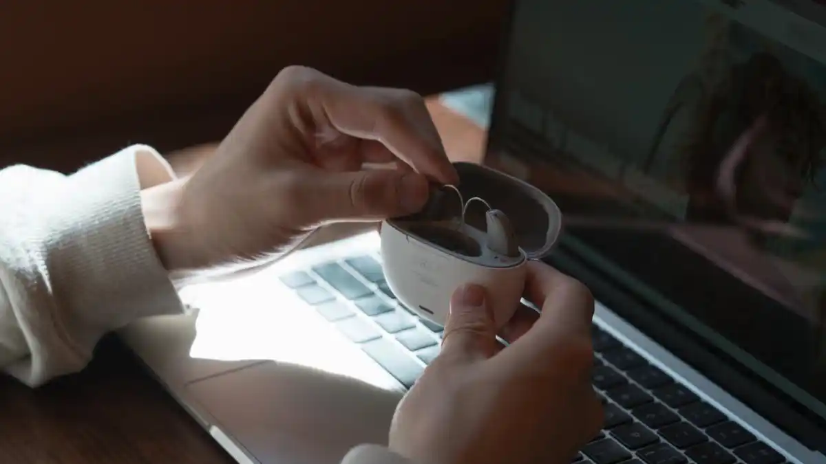 Two ORKA O1 RIC hearing aids inside charging case in front of computer