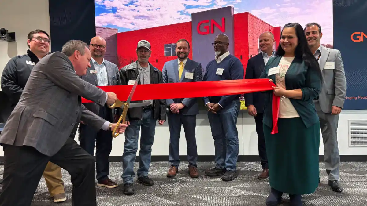 Tom Woods, President of GN Hearing North America, cuts the ceremonial ribbon on the new facility as GN staff members and Shakopee representatives cheer him on.