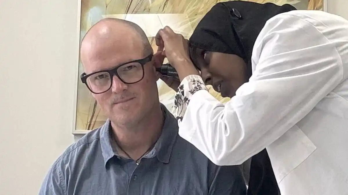 Photo of man having ear canal inspected via otoscophy