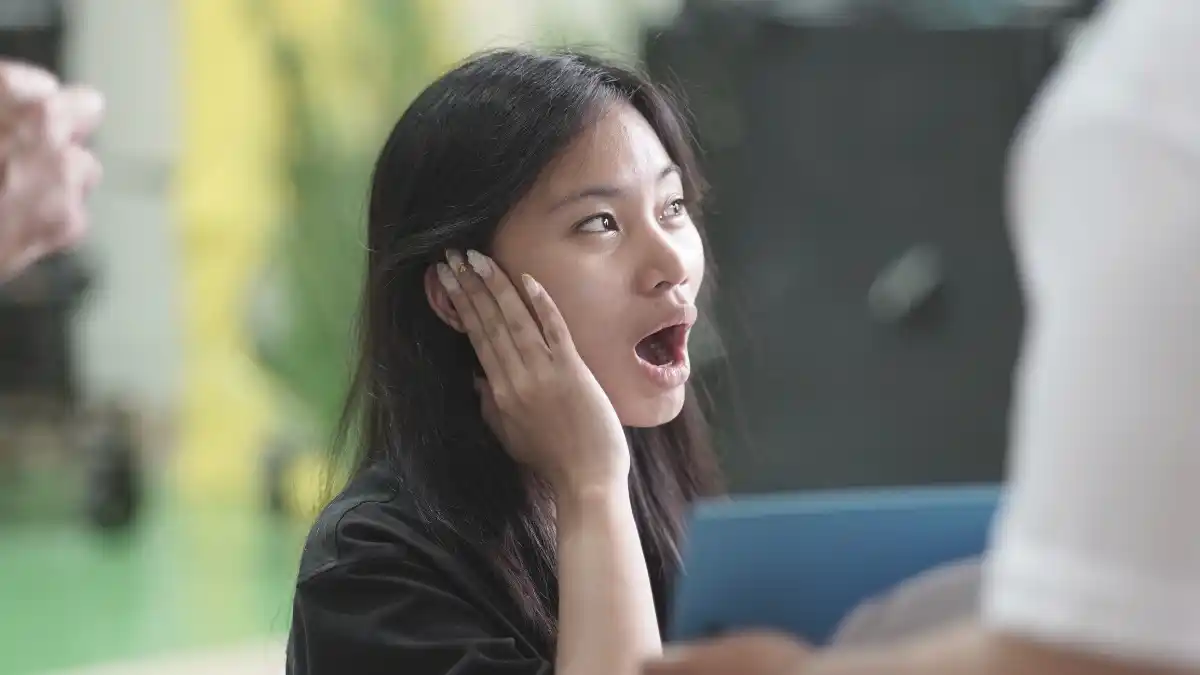 A young woman reacts to amplified sound from a hearing aid.