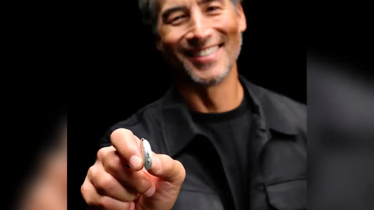 Small Starkey Omega AI+ RIC hearing aid in man's fingers