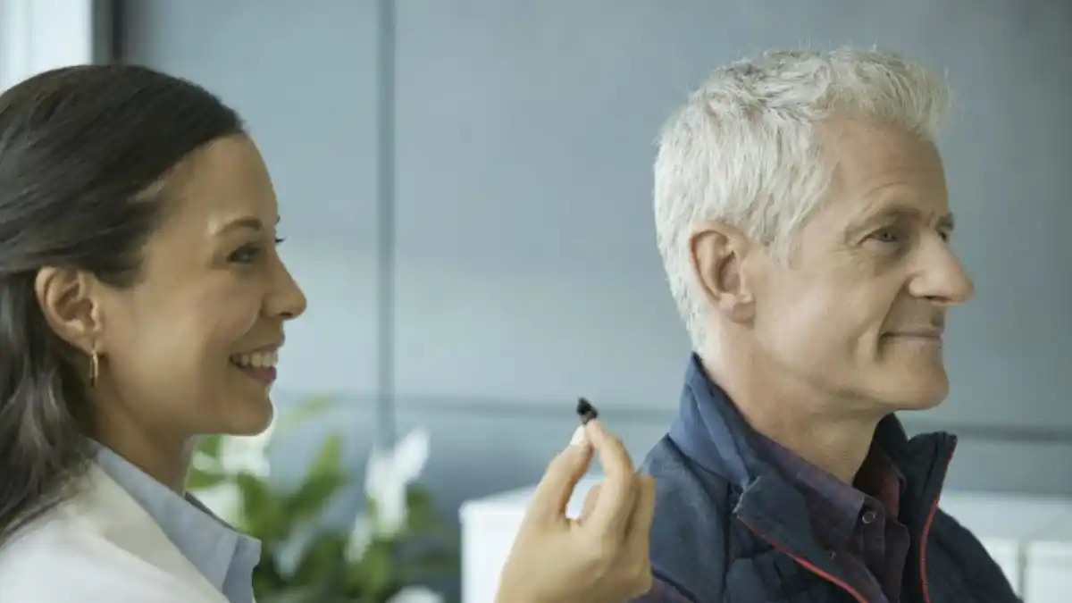 Photo of Audiologist holding a CIC hearing aid next to a patient