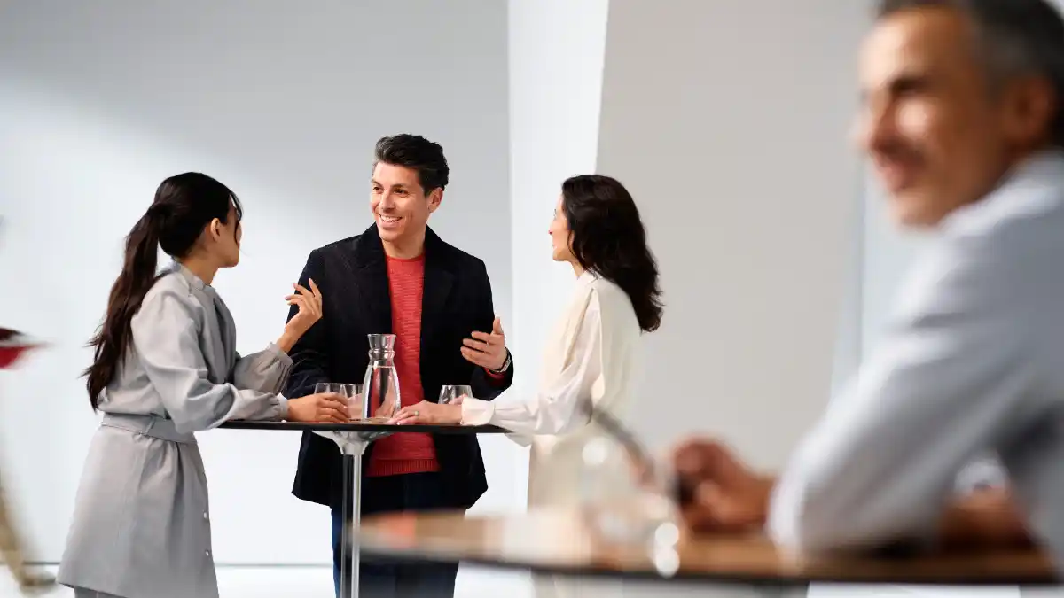 Three people talking at a table in noisy background