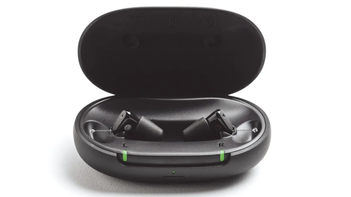 Two black Sony CRE-C20 hearing aids in oval portable charging case