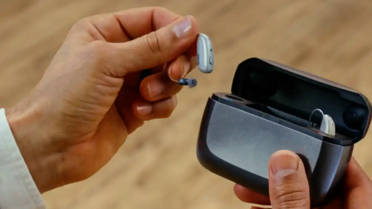 Man holding Jabra Enhance Select M3 next to charger