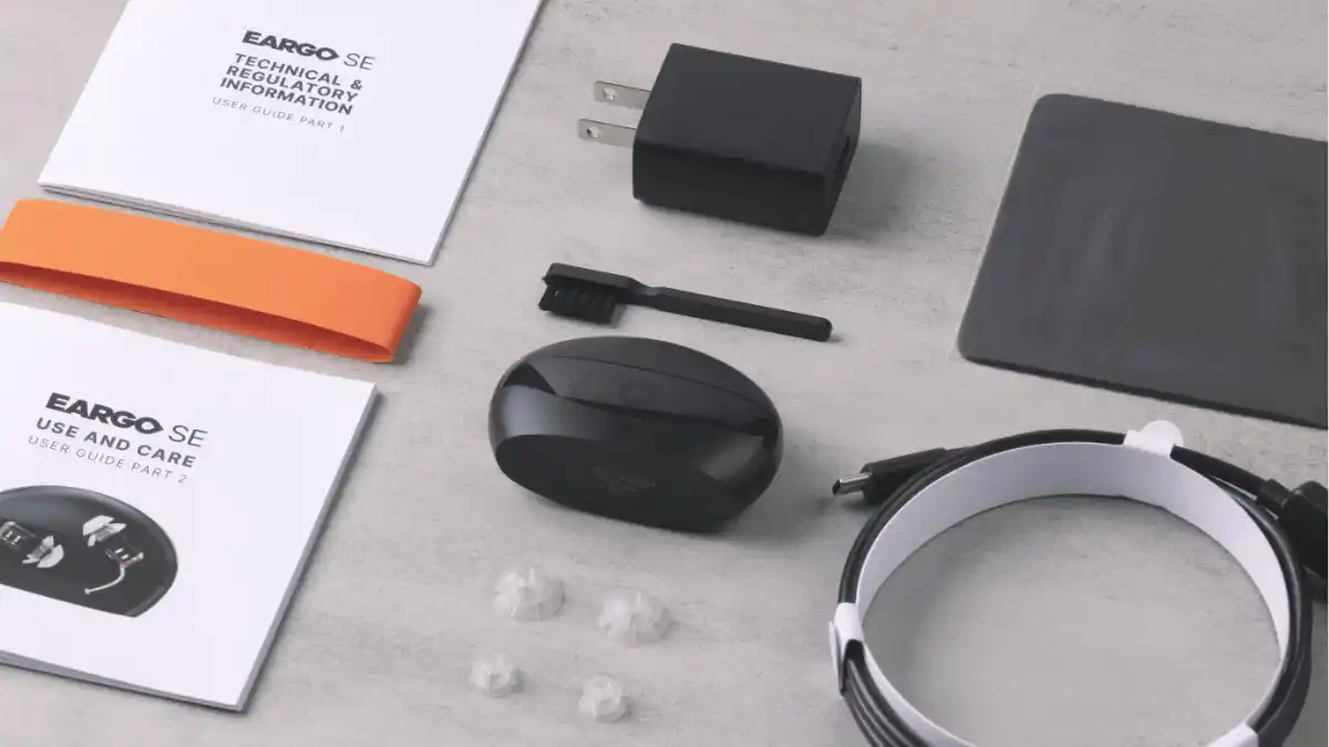 The Eargo SE package unboxed. The purchase of Eargo SE includes a set of two CIC hearing aids and charger, three eartips, a USB/Type C cable and power cube, cleaning brush, instruction manual, free onboarding and lifetime remote support/service, a 45-day trial period, and a 1-year limited warranty.