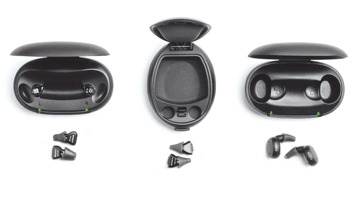 Three black Sony in-ear and earbud OTC hearing aids and charging cases